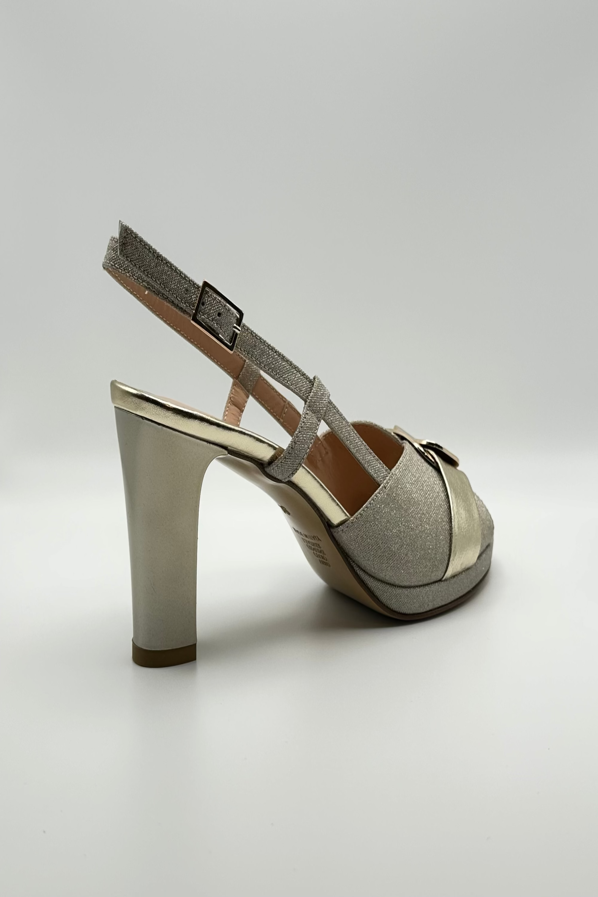 Platinum  high-heeled sandal with strap on a light gray background