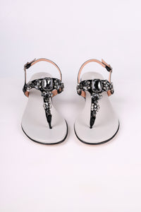 Pair of Black sandals with black low heels embellishments on a white background