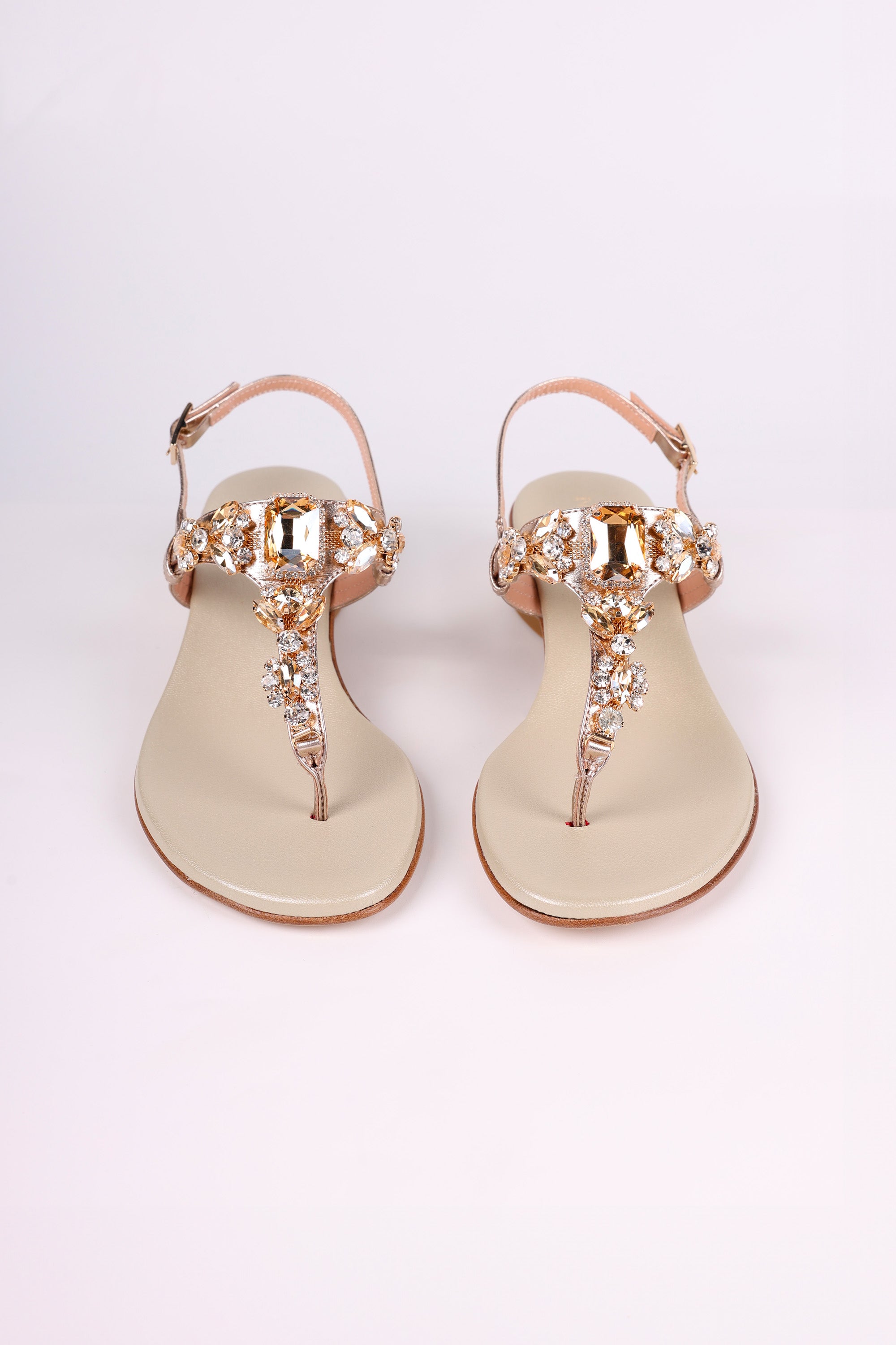 Pair of Platinum  sandals low heels with gold embellishments on a white background