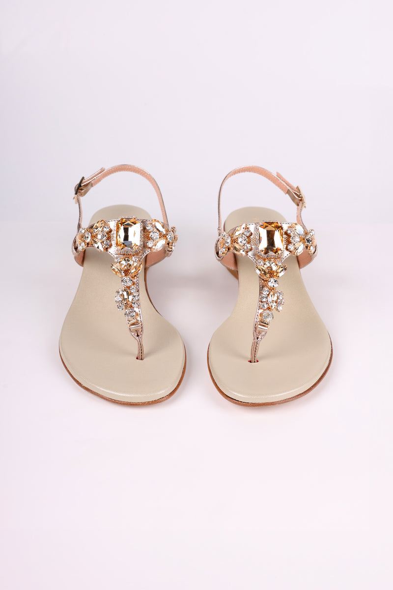 Pair of Platinum  sandals low heels with gold embellishments on a white background