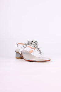 White sandal low heels with decorative straps and embellishments on a white background