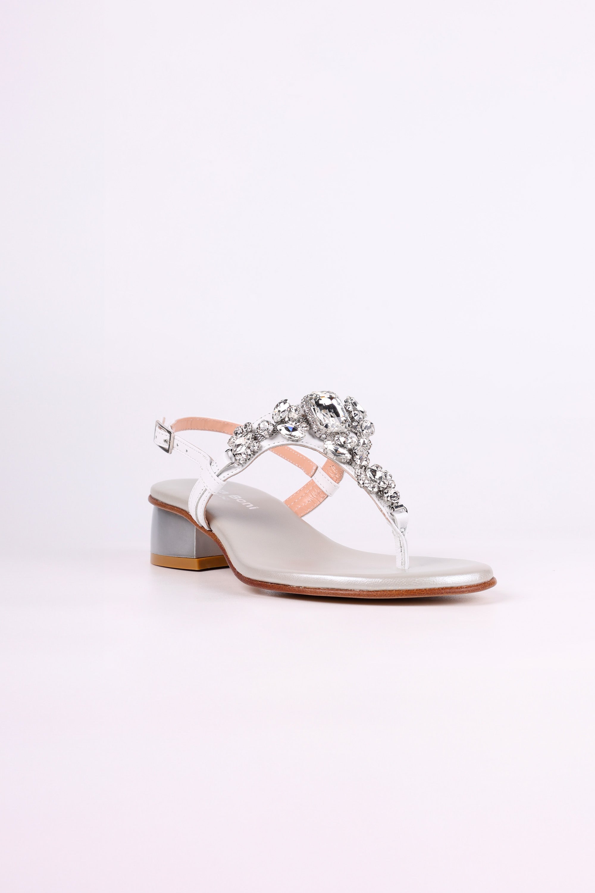 White sandal low heels with decorative straps and embellishments on a white background