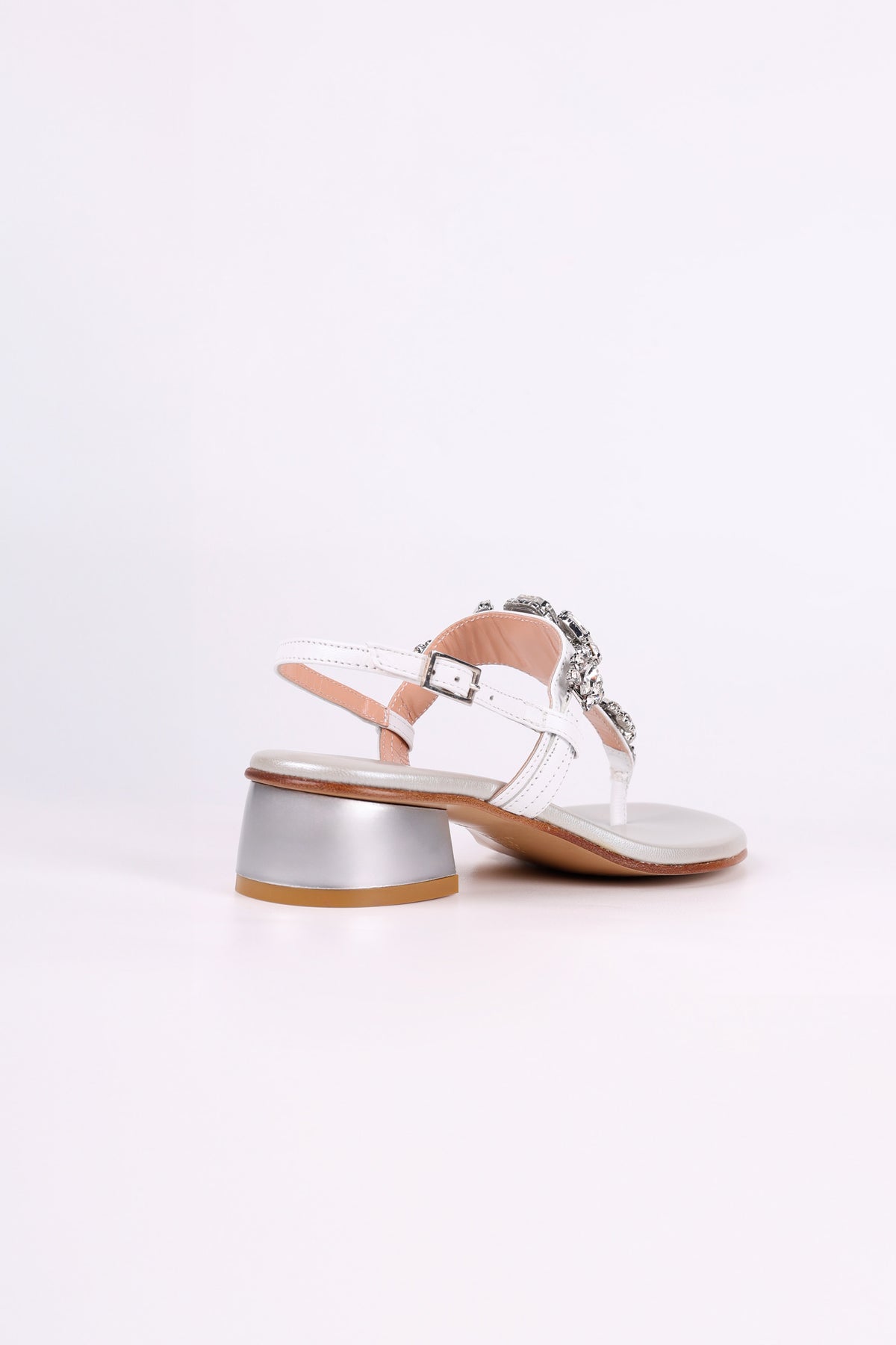 White sandal low heels 
with a block heel on a light pink background