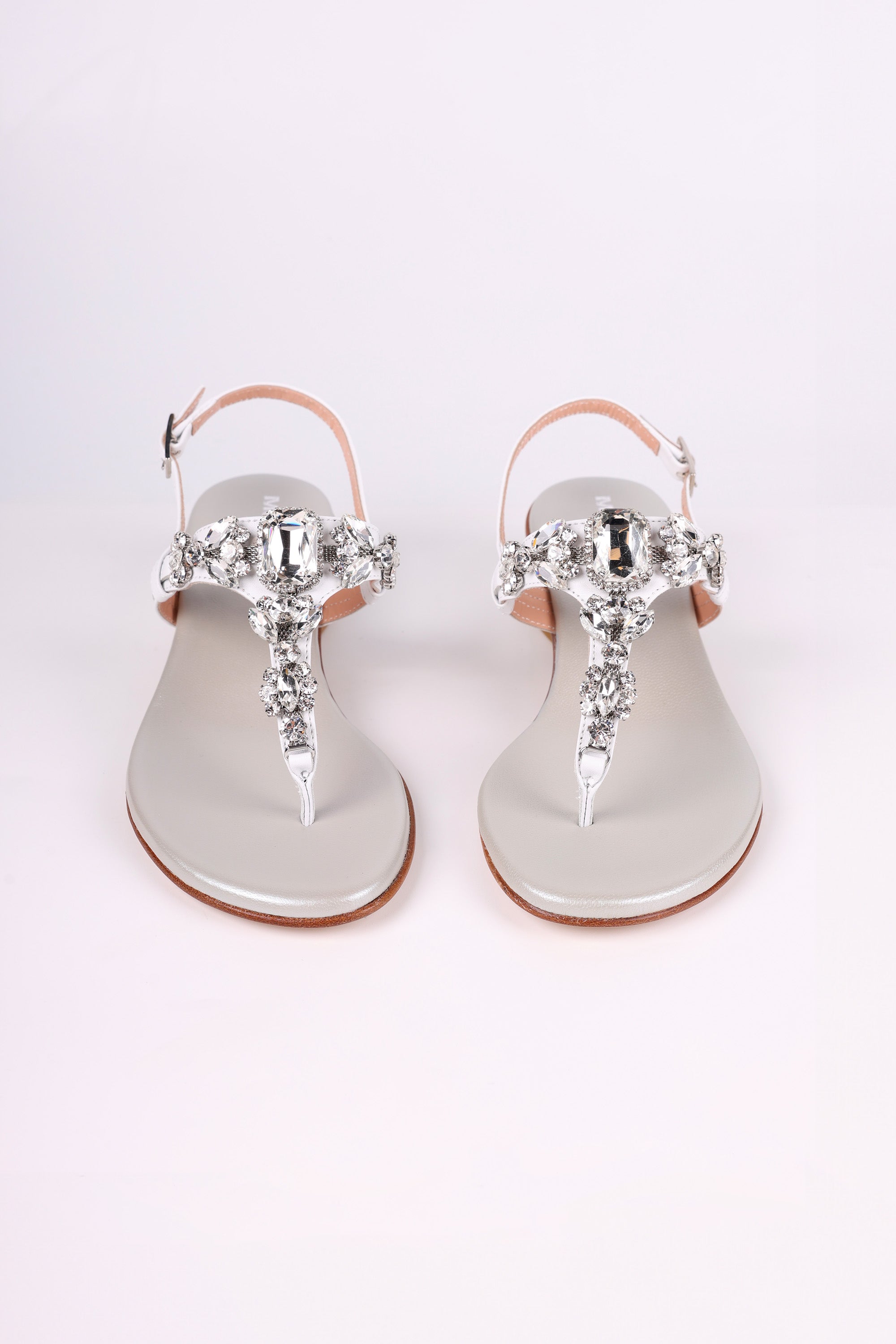 Pair of white embellished sandals low heels on a white background