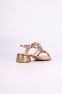 Platinum sandal low heels with embellishments on a light pink background