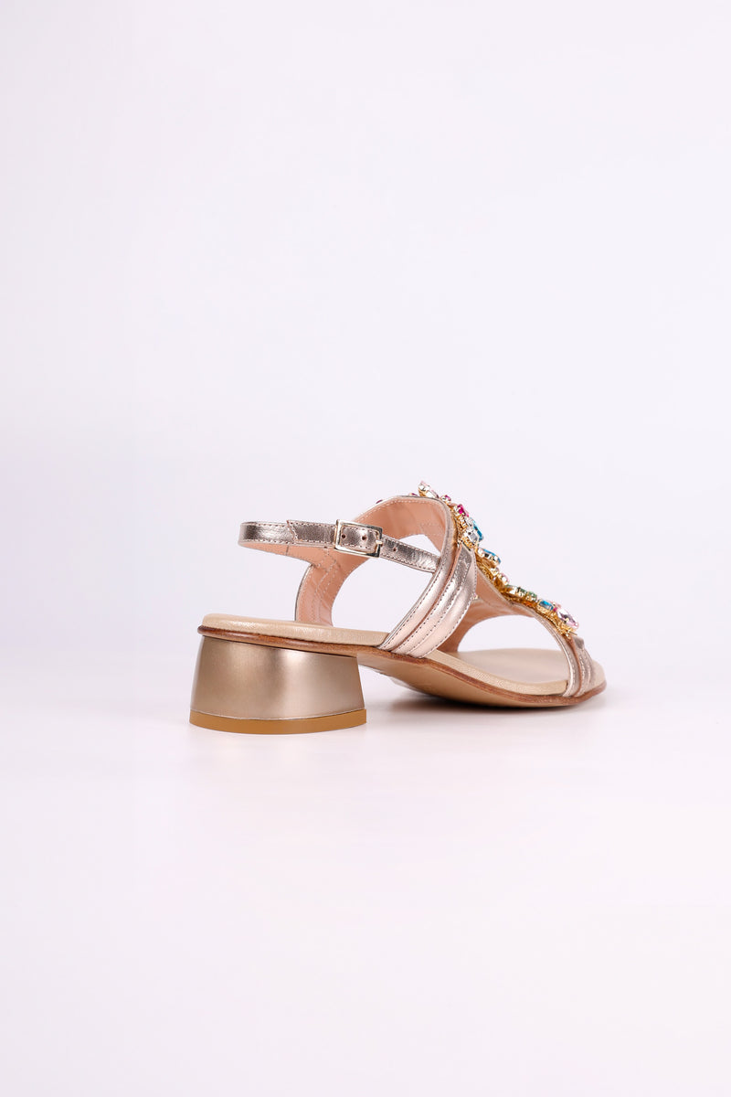 Platinum sandal low heels with embellishments on a light pink background