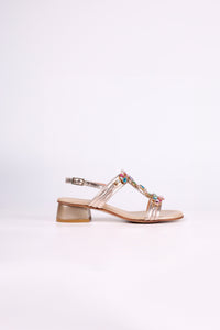 Platinum sandal low heels with colorful embellishments on a light pink background
