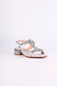 Silver sandal low heels with decorative straps on a light gray background