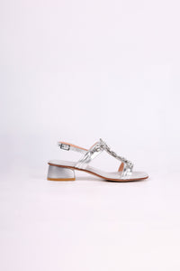Silver low heels sandal with a decorative strap on a white background